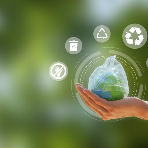 Zero waste. hand holding the earth that plastic bag covering on a green background.